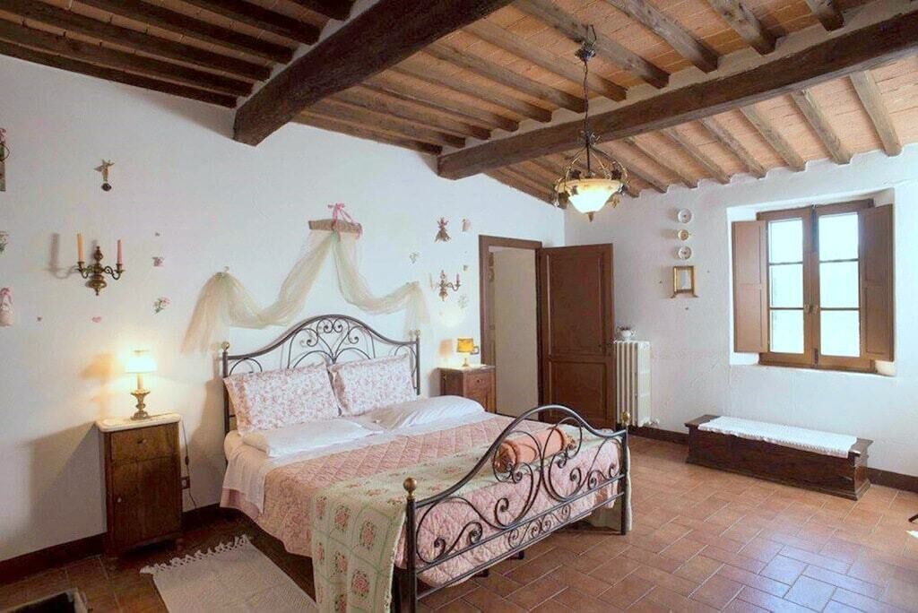 A bedroom with a bed, bedside tables, a bench, and a window.