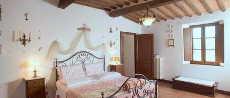 A bedroom with a bed, bedside tables, a bench, and a window.