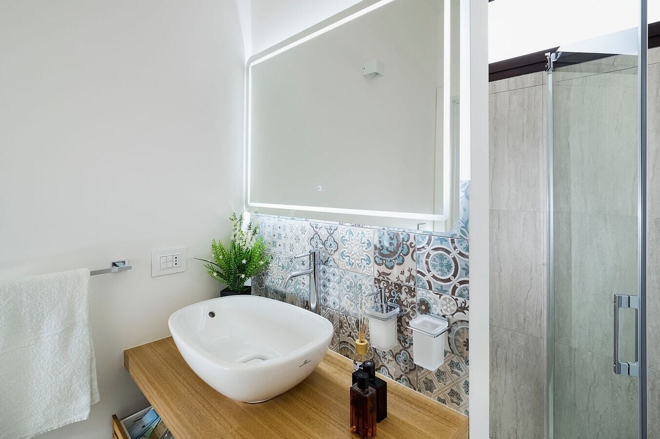 Ein modernes Badezimmer mit einem freistehenden Waschtisch, einer Duschkabine aus Glas und einer dekorativen Rückwand.