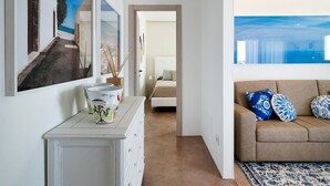 Un couloir avec une commode blanche, un lit et un canapé à motifs bleus et blancs.