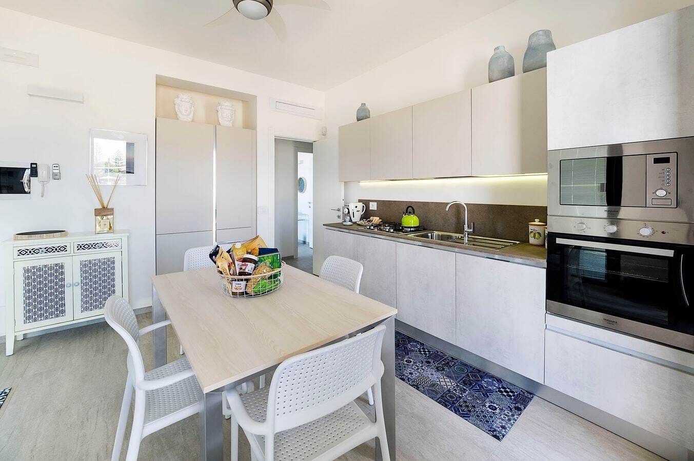 A modern kitchen with white cabinetry, a dining table with chairs, and a built-in oven.