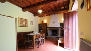 A dining area with a wooden table and chairs, a fireplace, and a kitchen area with cabinets and a stove.