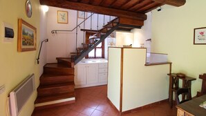 A staircase leading to a kitchen with white cabinets and a wooden ceiling.