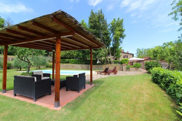 Área externa coberta com mesa de bilhar, assentos e uma parede de pedra ao fundo.