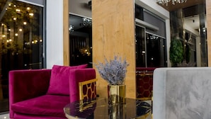 A modern lobby with a round glass table, a plush red sofa, and a decorative vase with flowers. - Badem Garden Apart Hotel (Tashkent)