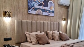 A modern bedroom with a large bed, a bedside table with a phone, and a wall-mounted air conditioner. - Badem Garden Apart Hotel (Tashkent)