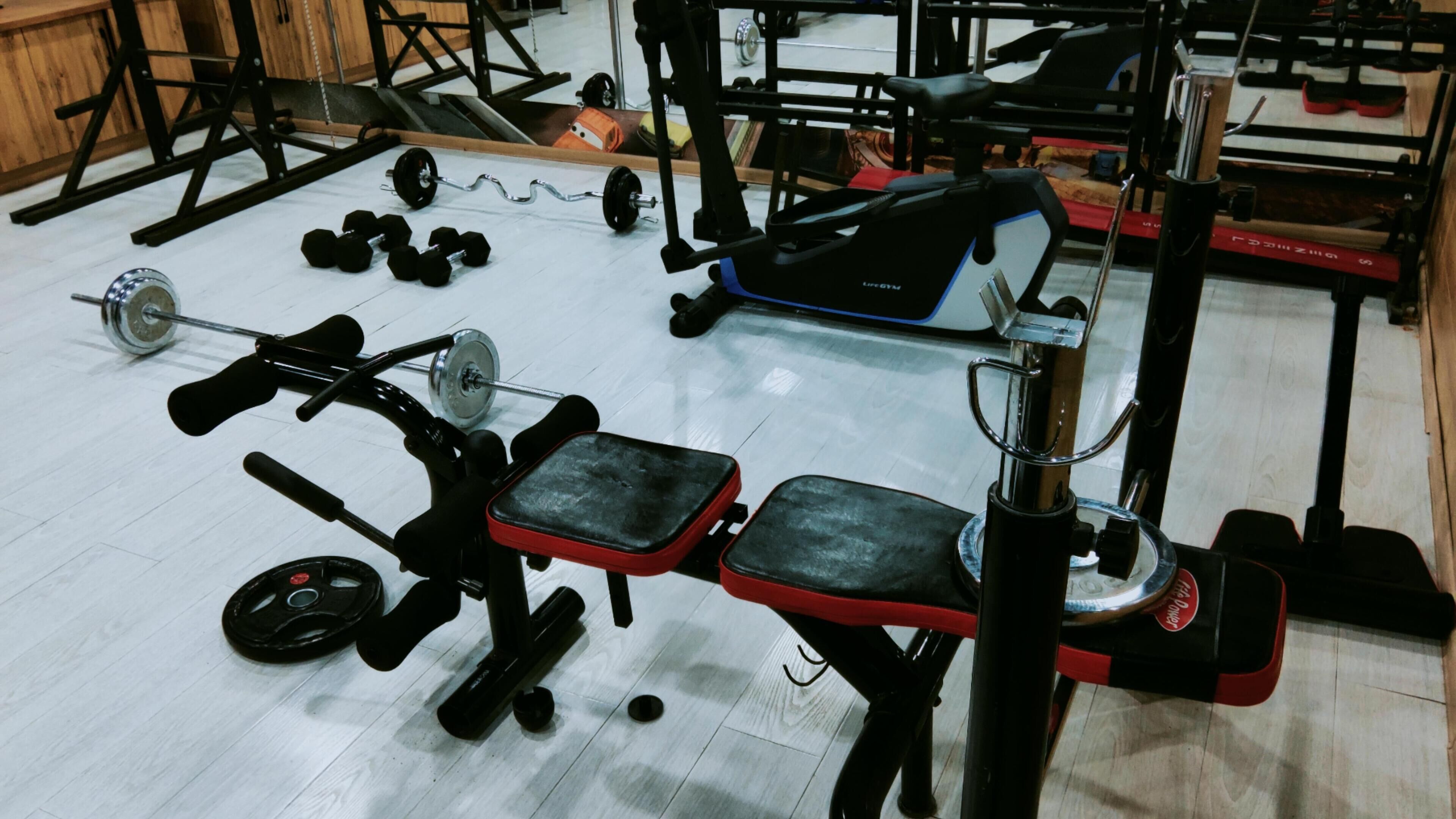 A gym with various exercise equipment including dumbbells, a bench press, and a weight machine.