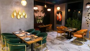 A modern dining area with green upholstered chairs, a wooden table set with plates and glasses, and pendant lighting. - Badem Garden Apart Hotel (Tashkent)