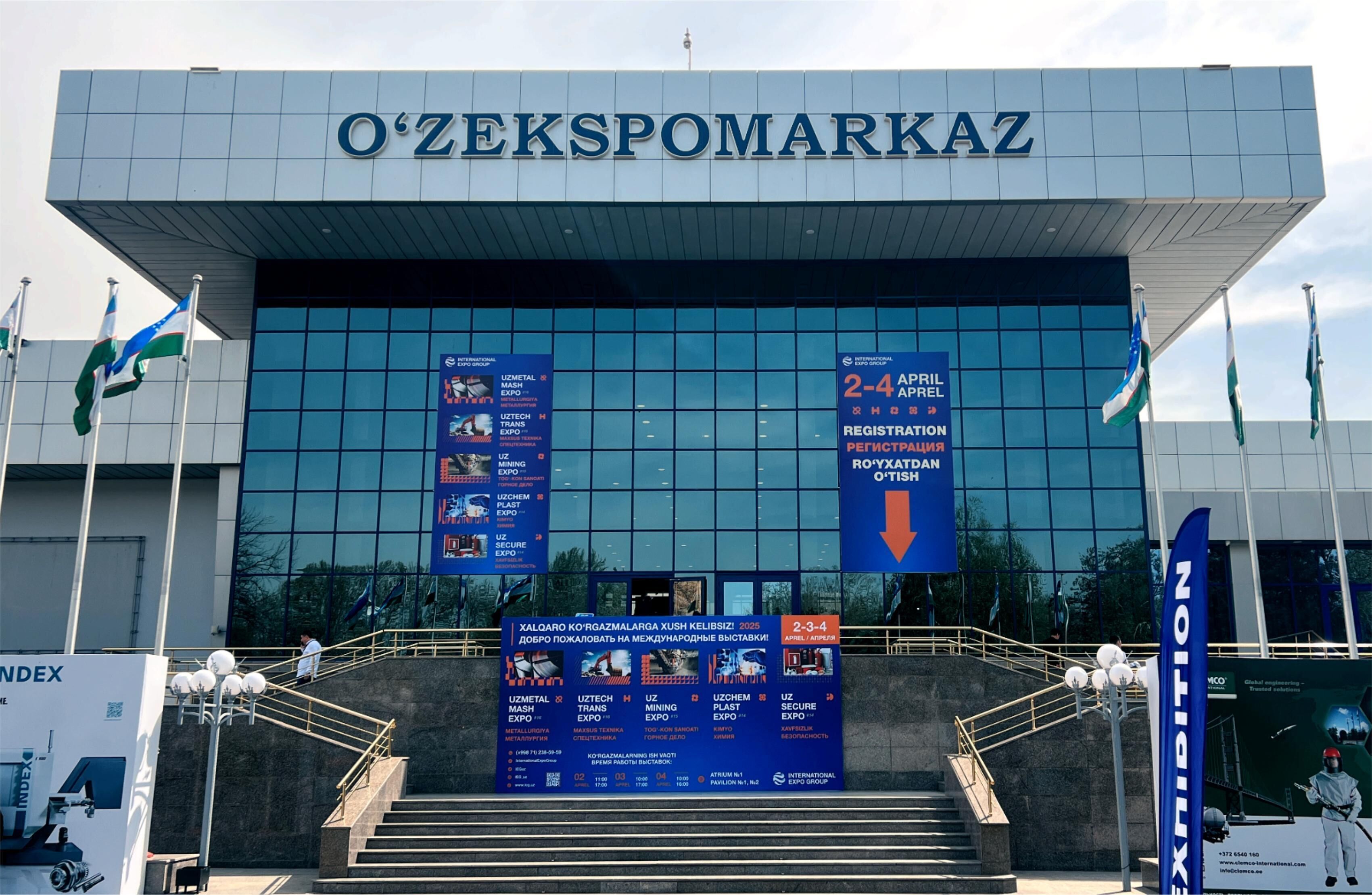 The exterior of O'ZEKSPOMARKAZ building with signage for various events and registration details.