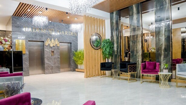 A modern lobby with a reception desk, seating area, and a sign reading "BADEM GARDEN". - Badem Garden Apart Hotel (Tashkent)
