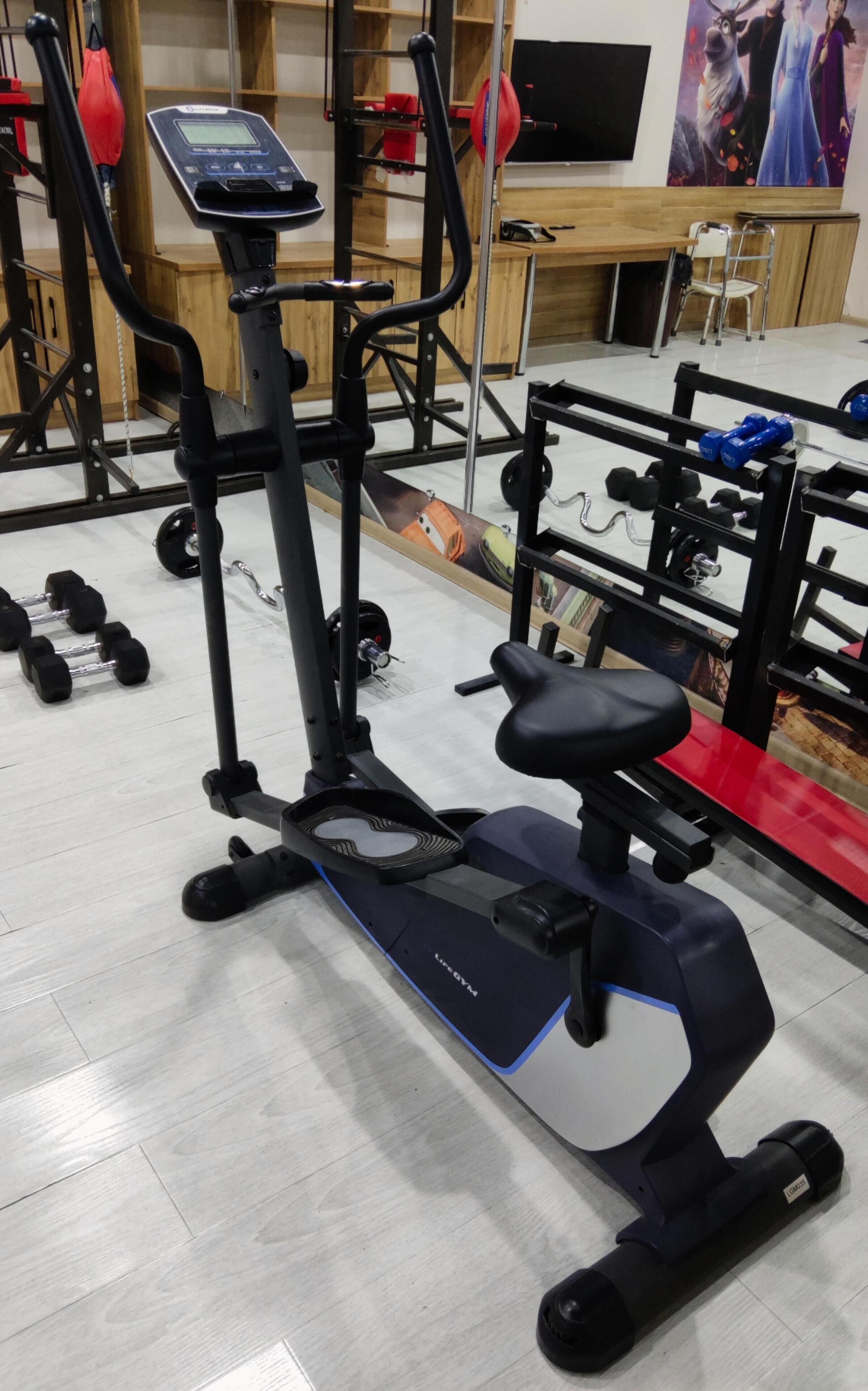 A gym with exercise equipment including an elliptical, weights, and a treadmill.