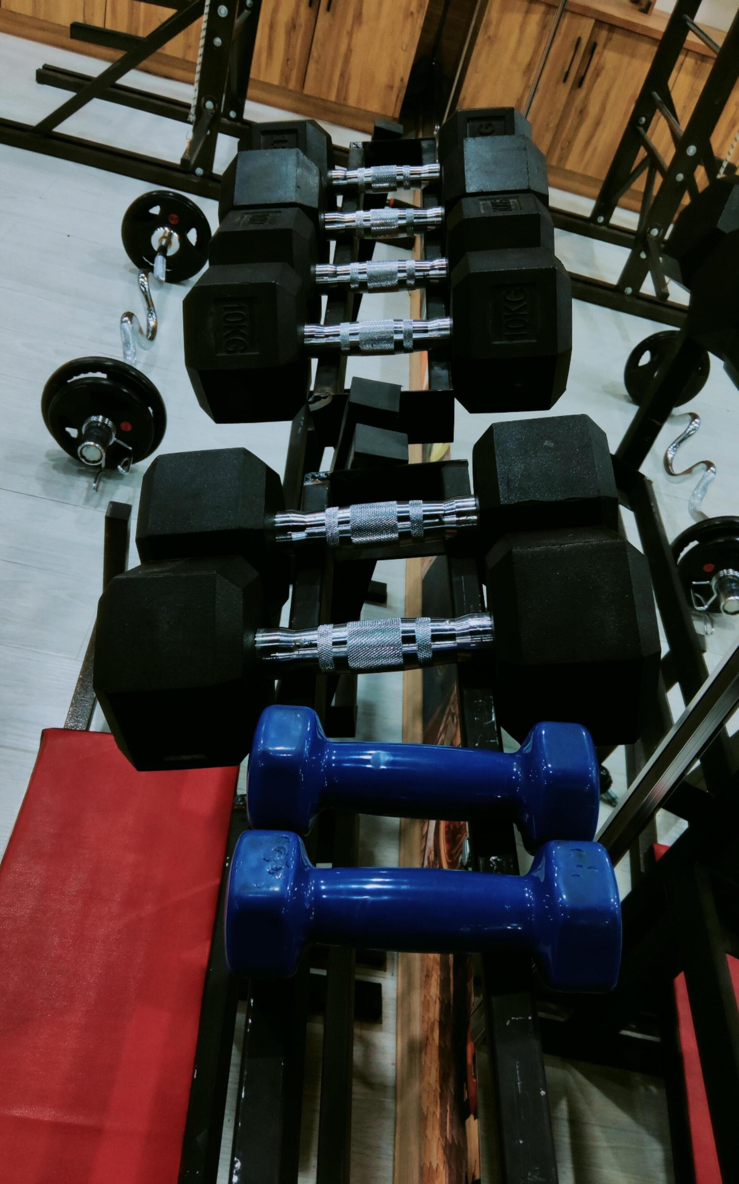 Uma academia com diversos equipamentos de musculação, incluindo halteres e barras.