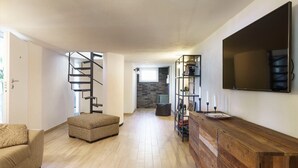 A modern living room with a spiral staircase, a wooden cabinet, and a flat-screen TV. - Casa Sul Mare - Sea front house (Punta Milocca)