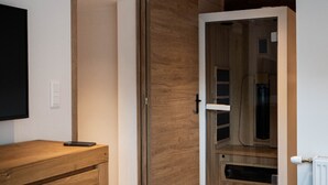 A room with a wooden cabinet, a sliding door, and a mounted television. - Luxury residence in Métabief, suites, apartments, private spa and sauna (Métabief)
