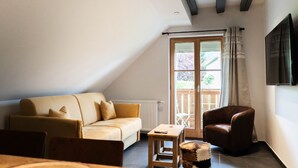 A cozy living room with a sofa, a chair, a small table, and a large window with a view of the outdoors. - Luxury residence in Métabief, suites, apartments, private spa and sauna (Métabief)