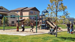 A playground with swings, slides, and climbing structures. - Spacious 5-BR Home: Private Hot Tub & Big Yard, Stocked Kitchen, Mountain View! (Colorado Springs)