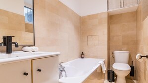 A modern bathroom with a white sink, a bathtub, and a toilet.