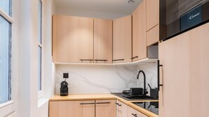 A modern kitchen with light wood cabinets, a black countertop, and a built-in oven.