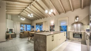 A spacious living area with a large island, a kitchen with modern appliances, and a dining area with a view. - Villa Zenais, Luxury with swimming pool (Koridallos)