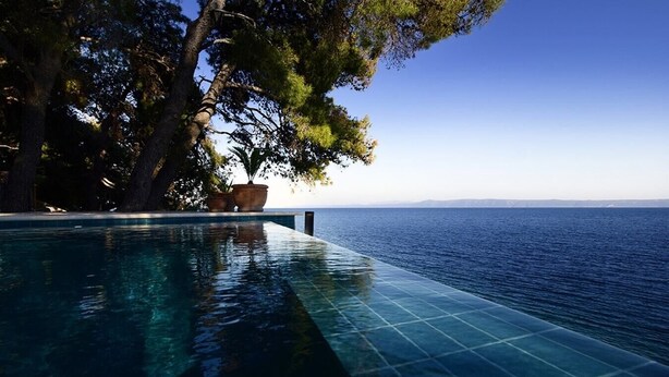 An infinity pool with a clear view of the sea, surrounded by trees and a clear sky. - Villa Josipa - Luxury modern villa with pool in Croatia (Puntinak)