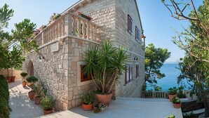 A stone building with a balcony overlooking the sea, surrounded by potted plants. - Villa Josipa - Luxury modern villa with pool in Croatia (Puntinak)