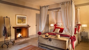 Una cama con dosel, chimenea, espejo y un cuadro en la pared.