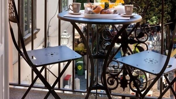 A balcony with two chairs and a table, overlooking a building with balconies and greenery. - Casa Mordigallina, in Sorrento Centre (Sorrento)