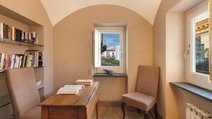 A cozy reading nook with a wooden table, two chairs, a bookshelf, and a window with a view of buildings. - Casa Mordigallina, in Sorrento Centre (Sorrento)