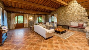 A spacious living room with a stone wall, wooden beams, and a fireplace. - Villa Biancospino - Private Villa with Pool (Chianni)