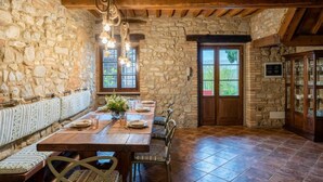 A rustic dining area with a stone wall, wooden beams, and a large table set for dining. - Villa Biancospino - Private Villa with Pool (Chianni)