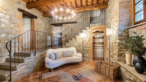 A stone-walled interior with a white sofa, a chandelier, and a staircase. - Villa Biancospino - Private Villa with Pool (Chianni)