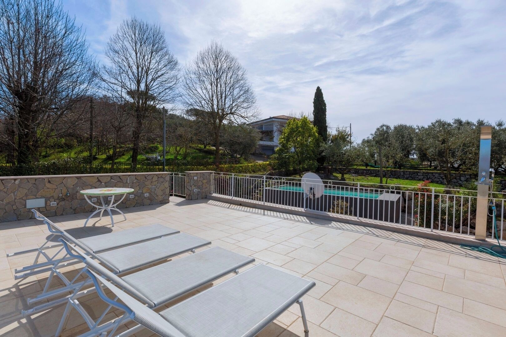 A rooftop terrace with outdoor seating, a pool, and a stone wall.