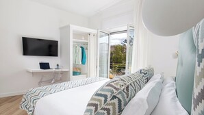 A bedroom with a bed, a TV, a desk with a laptop, and an open closet with clothes and a handbag. - Resort Lubrense - perfect for large groups (Sant'Agata Sui Due Golfi)