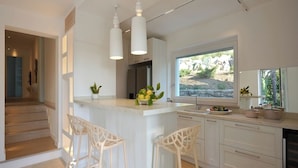 A modern kitchen with a central island, white bar stools, pendant lighting, and a view of the outdoors. - Resort Lubrense - perfect for large groups (Sant'Agata Sui Due Golfi)