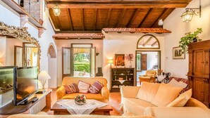 Un salon chaleureux avec un plafond en bois, une télévision, un canapé et une table basse.