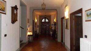 A hallway with a wooden floor, a chandelier, and a door at the end.