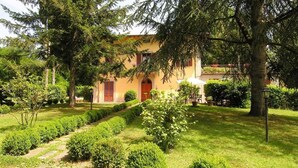 A building with a red door, surrounded by a well-maintained garden with trimmed bushes and a pathway.