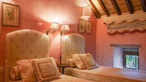Ein Schlafzimmer mit zwei großen, gepolsterten Kopfteilen, einem kleinen Tisch, zwei Lampen und einem Kamin.