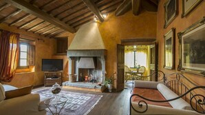Una sala de estar acogedora con chimenea, televisor y comedor con mesa y sillas.