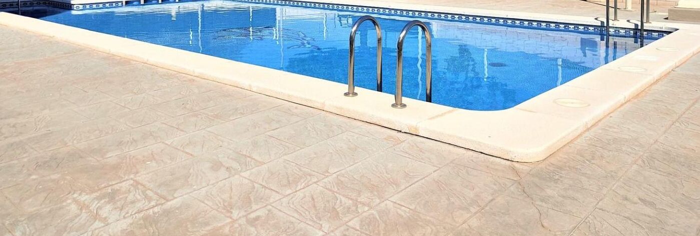 Une piscine dotée d’une plage carrelée et de rampes en métal.