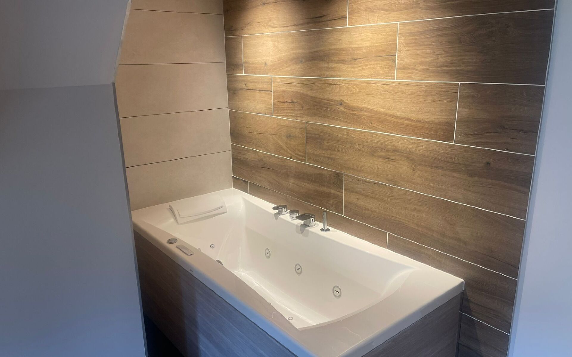 A modern bathroom with a freestanding bathtub, wooden wall tiles, and a white sink.