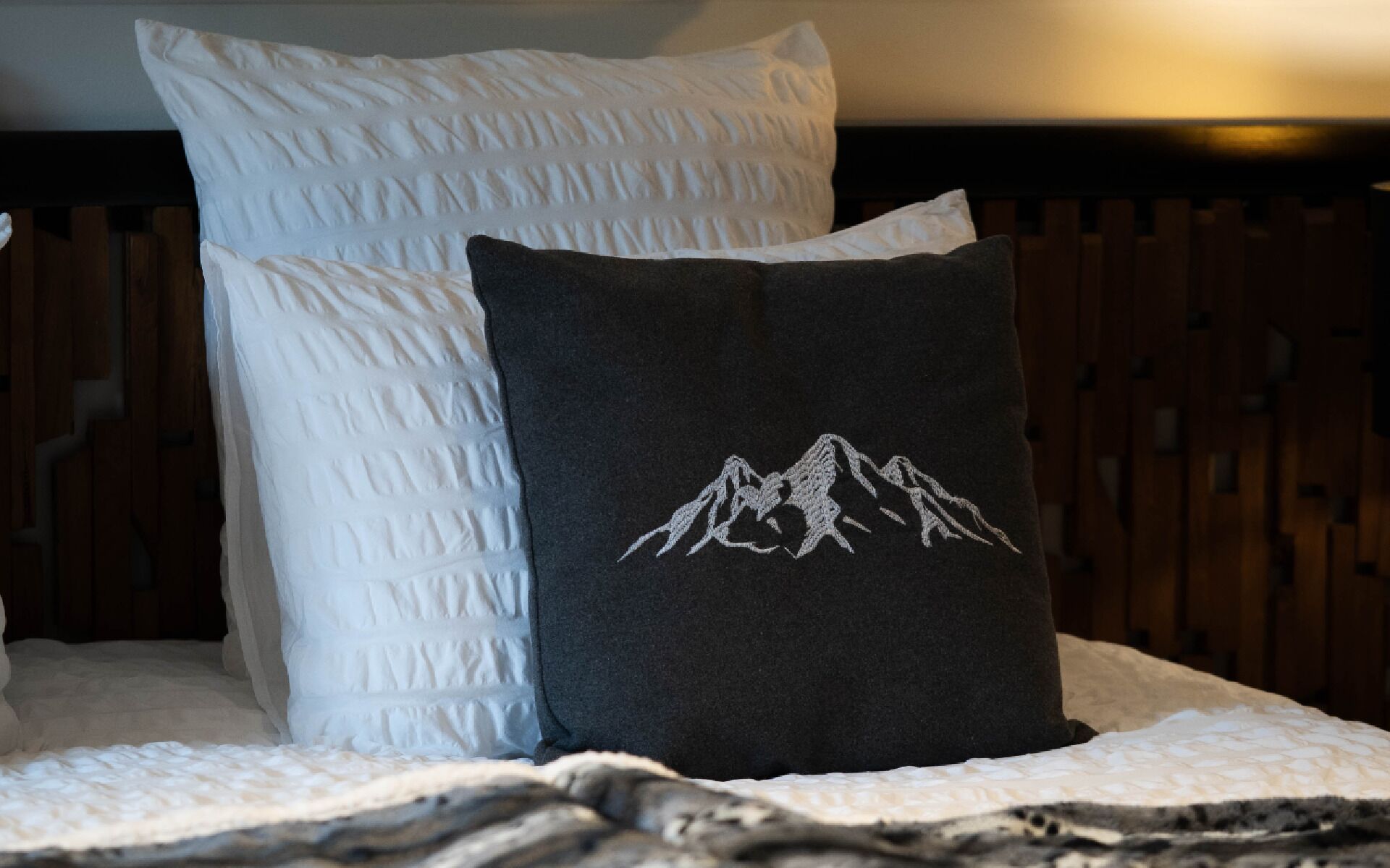 Ein Bett mit zwei Kissen, eines schlicht und eines mit einem Bergmotiv.