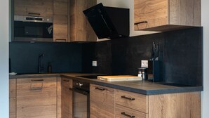 Une cuisine moderne avec des meubles en bois, un plan de travail noir et un four encastré.