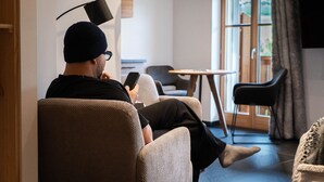 Une personne est assise dans un salon moderne, avec un canapé, une petite table et une chaise.