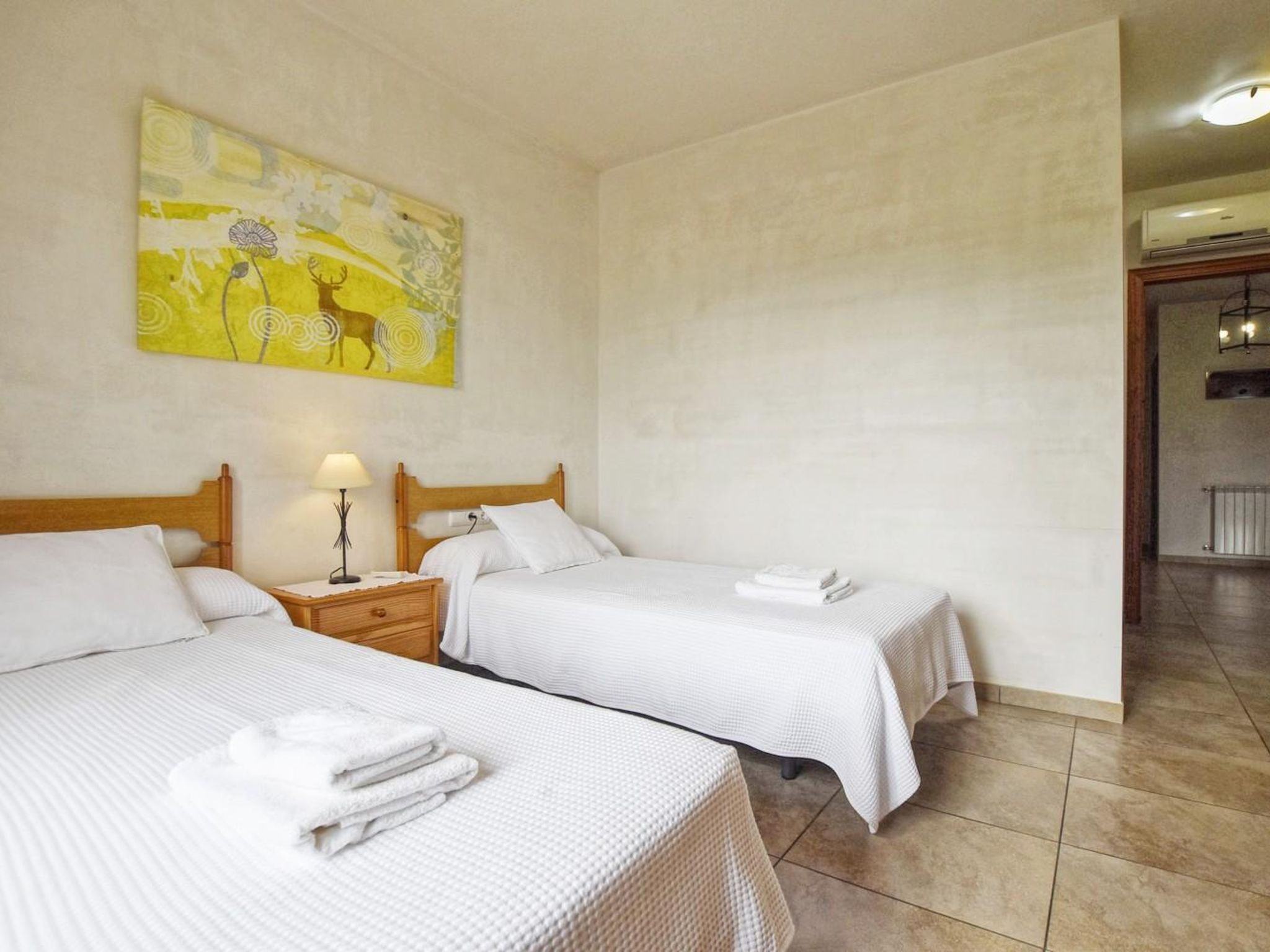 A hotel room with two beds, a nightstand with a lamp, and a painting on the wall.
