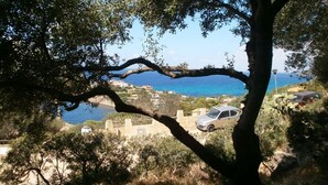 A coastal view with a tree in the foreground, a parked car, and buildings in the background. - Villa Mavriana - Private villa with sea views (Torre Delle Stelle (Maracalagonis))
