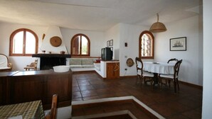 A spacious living area with a fireplace, a dining table, and a television. - Villa Mavriana - Private villa with sea views (Torre Delle Stelle (Maracalagonis))