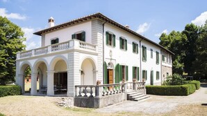 A large, white building with green shutters, a balcony, and a central entrance with steps. - Villa Betti - Private villa with pool in Tuscany (Dicomano)