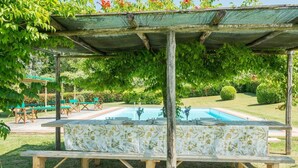 An outdoor pool area with a covered seating area and picnic tables. - Villa Betti - Private villa with pool in Tuscany (Dicomano)