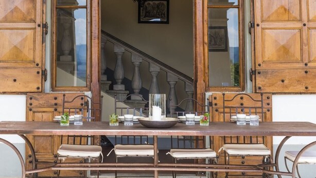 A wooden table with a bowl and glasses, set against a backdrop of a staircase and framed artwork. - Villa Betti - Private villa with pool in Tuscany (Dicomano)